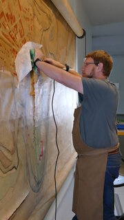 Restaurator beim Andrücken von einer Verklebung an einer riesigen hängenden Karte.