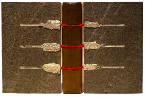 Einband mit offenem Falz, braunem Lederrücken, roter Heftung und Deckeln aus Stein, dekoriert mit geschmolzenem Metall.